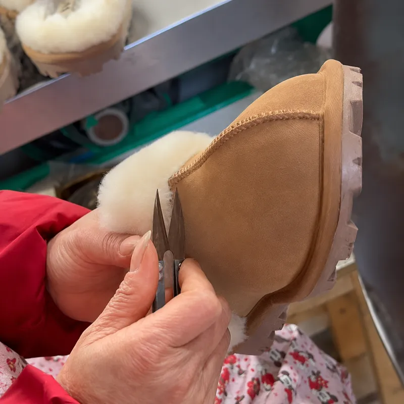 Worker trimming loose fibers on a plush slipper before packing